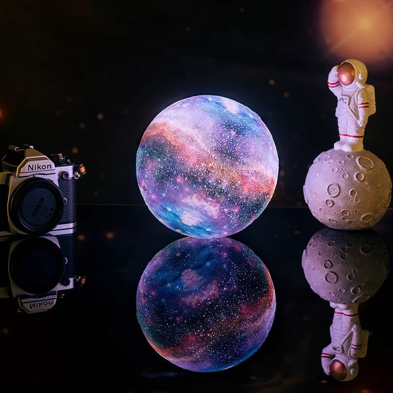 Decorative setup with a camera, galaxy-themed orb, and astronaut figurine on a reflective surface.