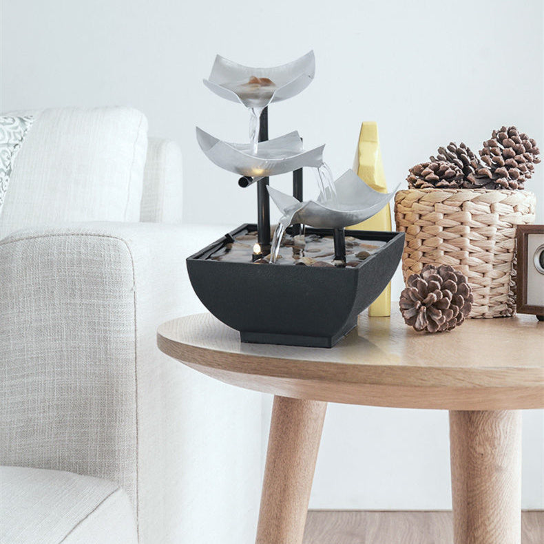 Decorative water fountain on a wooden table with pinecones and a basket in the background.