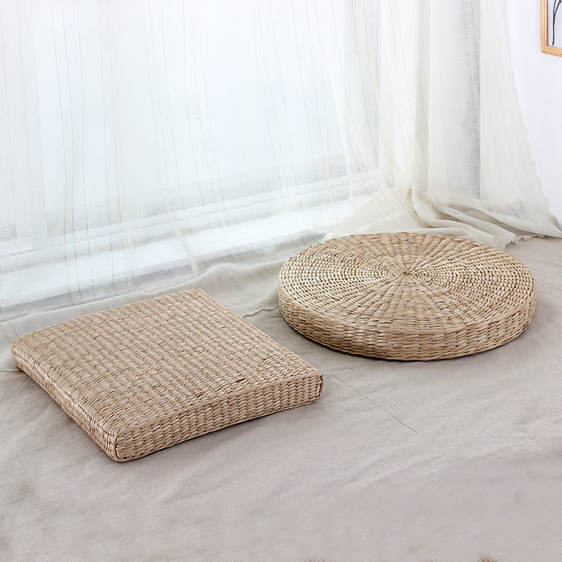Two woven floor cushions on a light-colored floor with white curtains in the background.