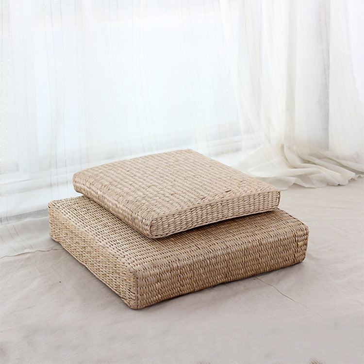 Two woven floor cushions on a light-colored floor with a white curtain in the background.