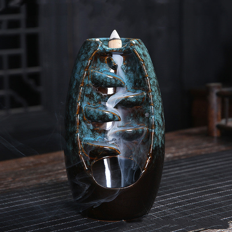 Decorative incense burner with a blue and black design on a dark surface.