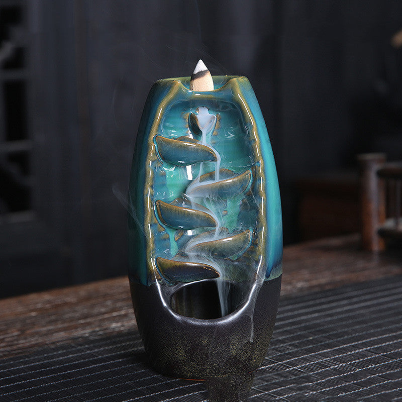 A blue decorative incense burner with smoke on a table