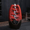 A red decorative incense burner with smoke on a wooden background