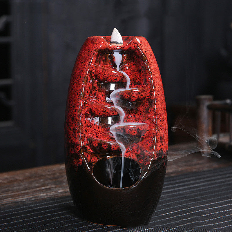 A red decorative incense burner with smoke on a wooden background