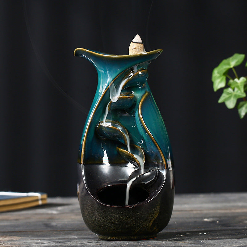 Decorative ceramic incense burner with a dark base and teal top on a wooden surface.