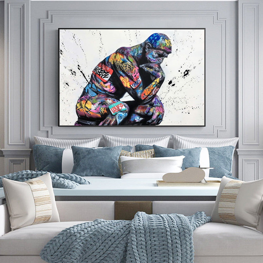 Colorful abstract painting of a thinker on a wall above a sofa with decorative pillows.