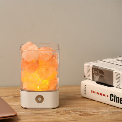 Picture of a salt lamp on a wooden surface next to some books.