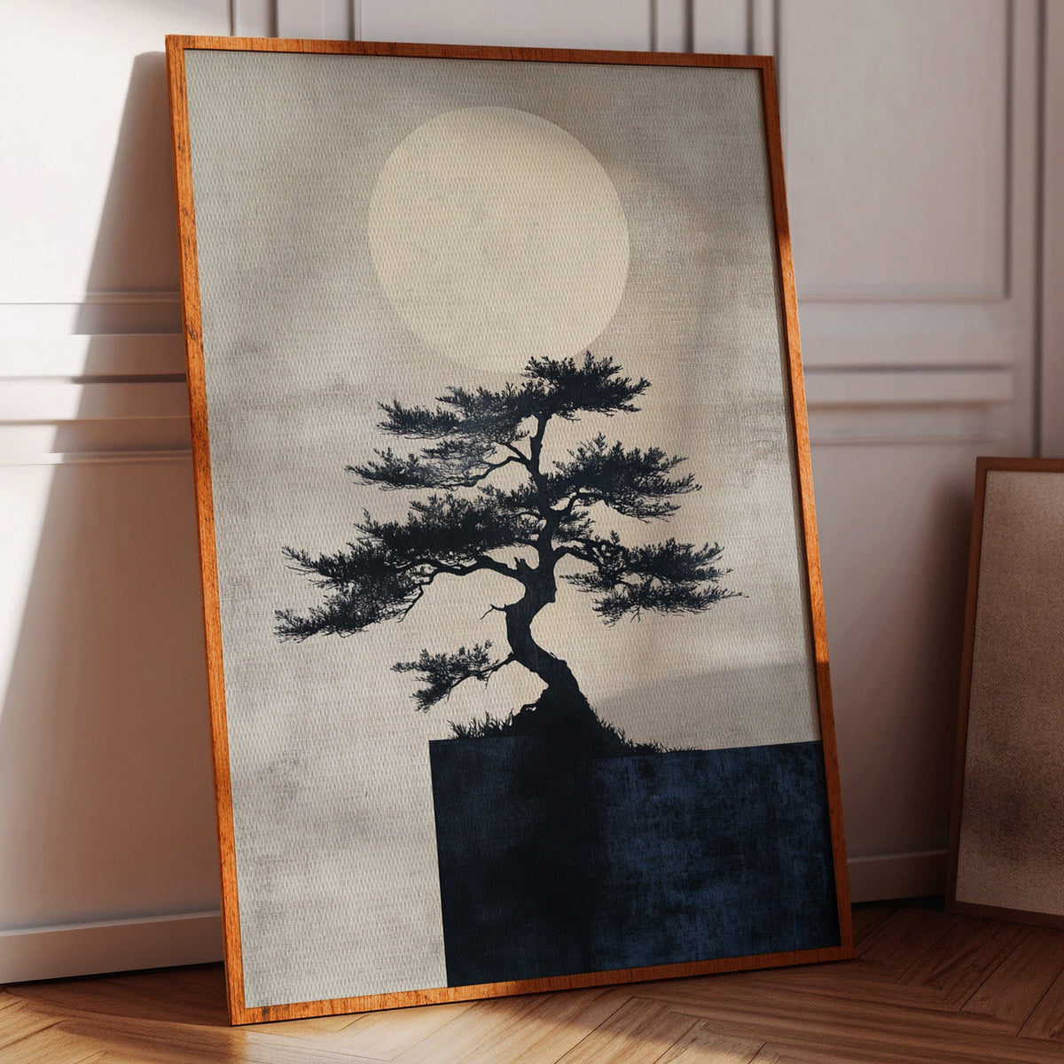 Framed artwork of a tree silhouette against a moonlit sky on a wooden floor.