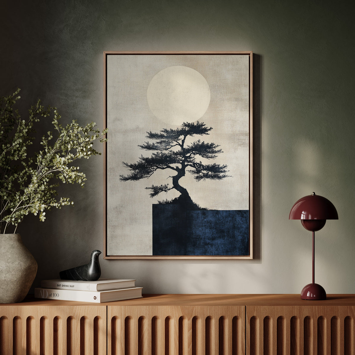Framed artwork of a tree silhouette against a moonlit sky on a wall above a wooden console table.