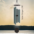 Solar-powered wind chime with 'Solar Singer 38' text against a sunset sky.