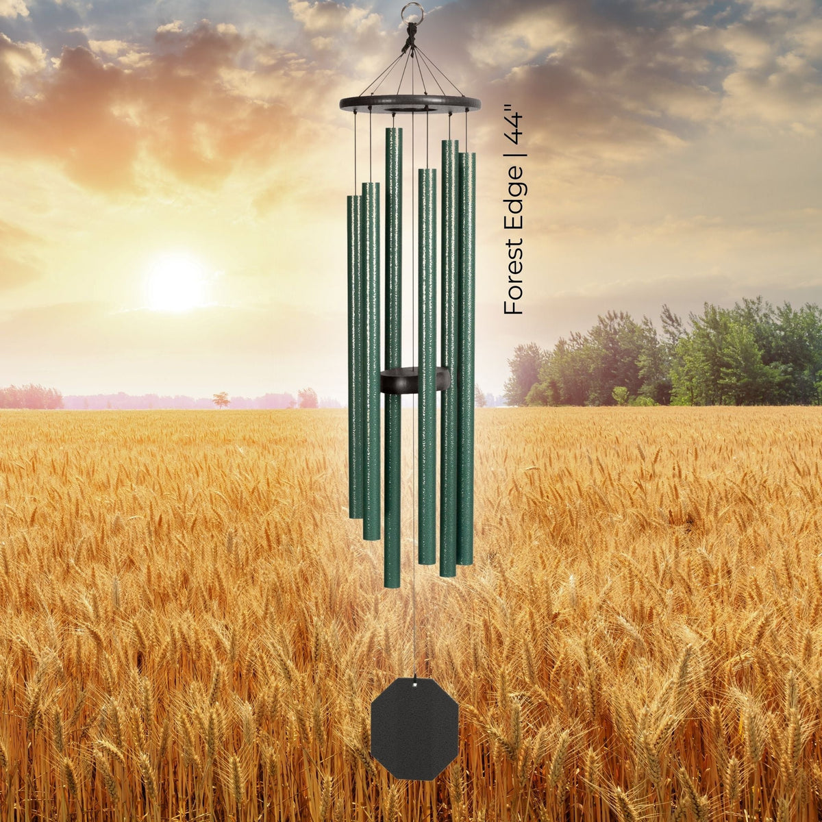 Green wind chime in a field with a sunset sky