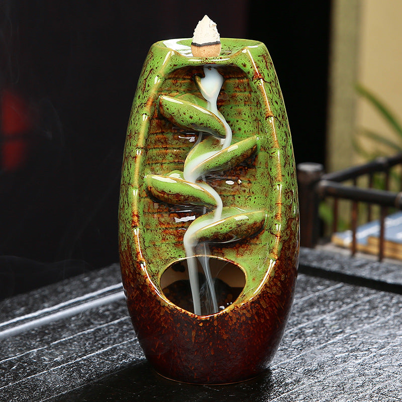 Ceramic incense burner with green and brown design on a dark surface