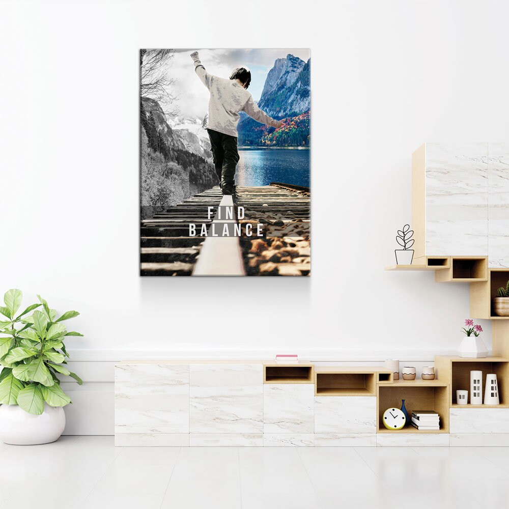 Poster of a person on a bridge with mountains and text 'Find Balance' in a modern room.