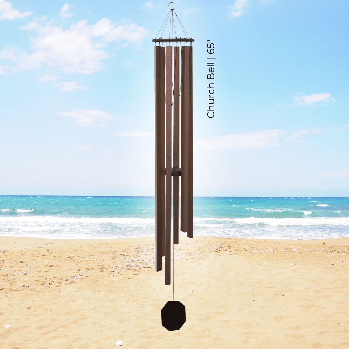 Brown wind chime on a sandy beach with ocean and blue sky in the background