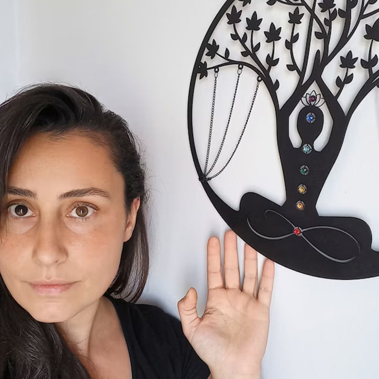Woman next to a decorative wall piece shaped like a tree with jewelry