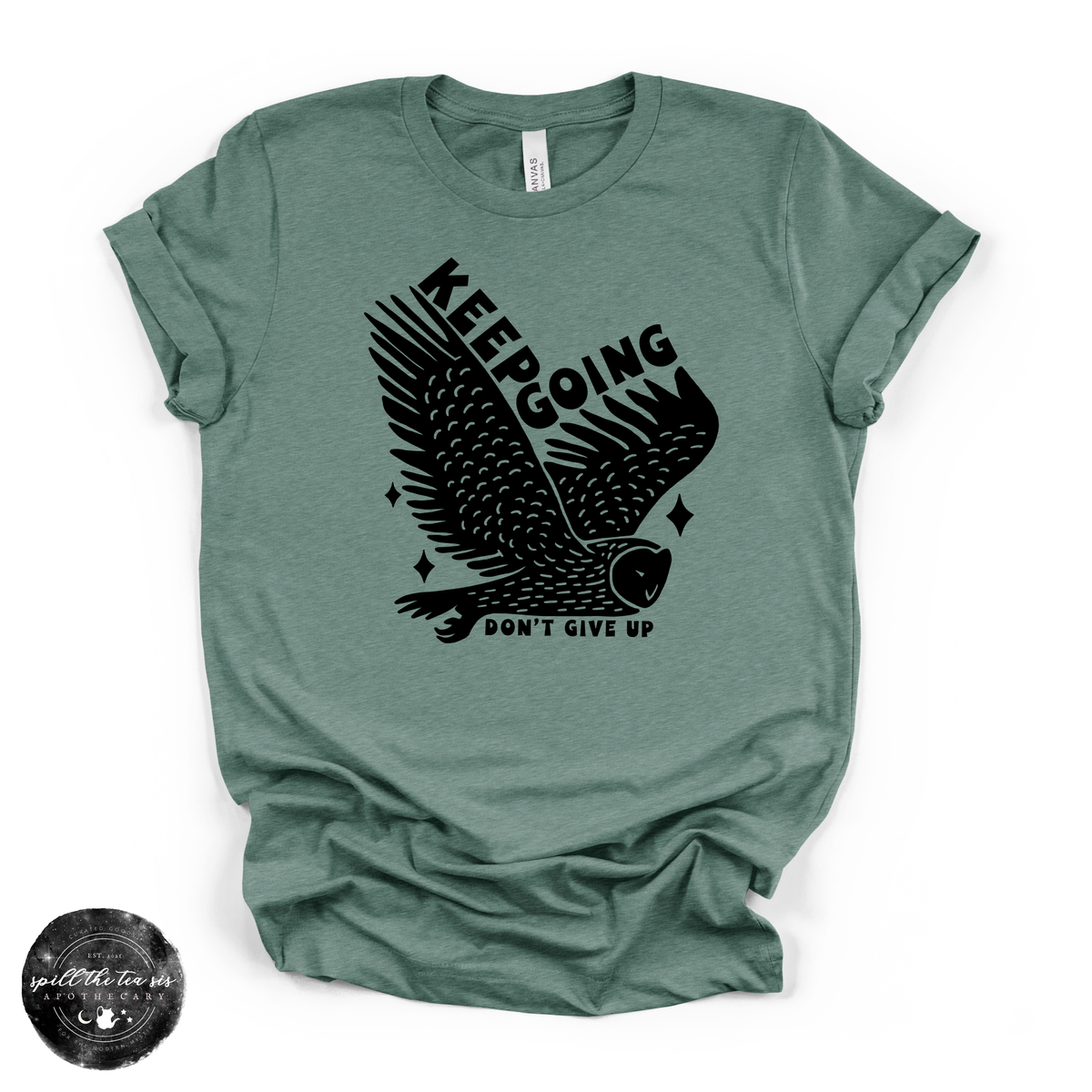 A heathered sage green short-sleeve t-shirt with a black graphic of an owl and the text 'KEEPING DON'T GIVE UP' on the front, displayed flat against a white background with a circular watermark in the bottom-left corner.