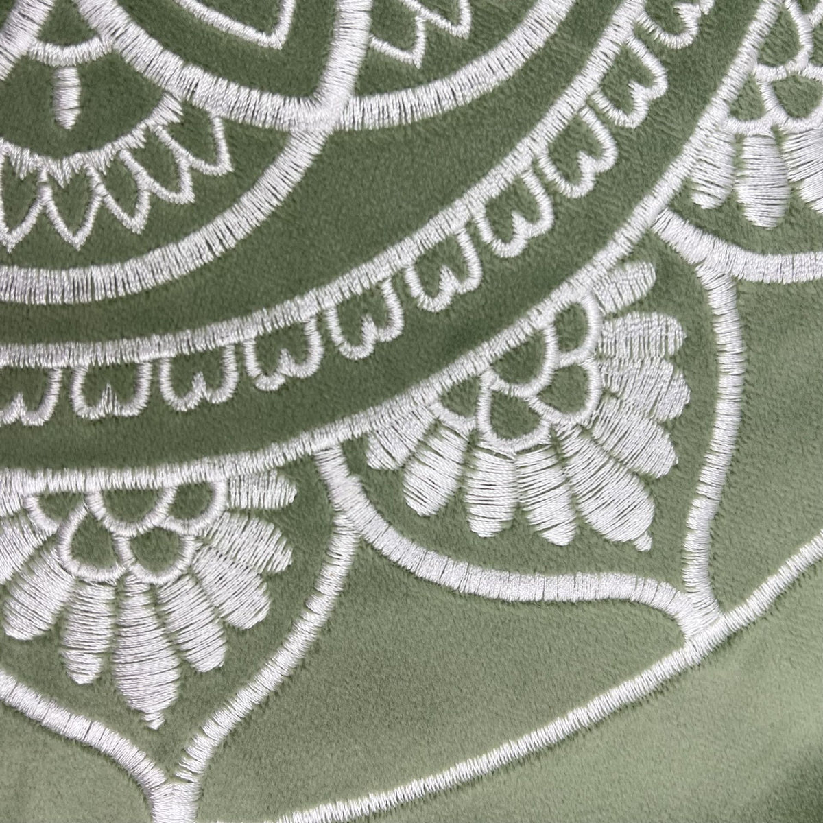Close-up of embroidered pattern on a green fabric background