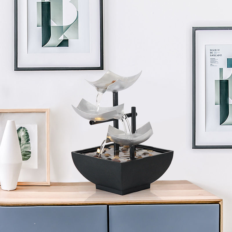 Decorative water fountain on a table with framed art in the background