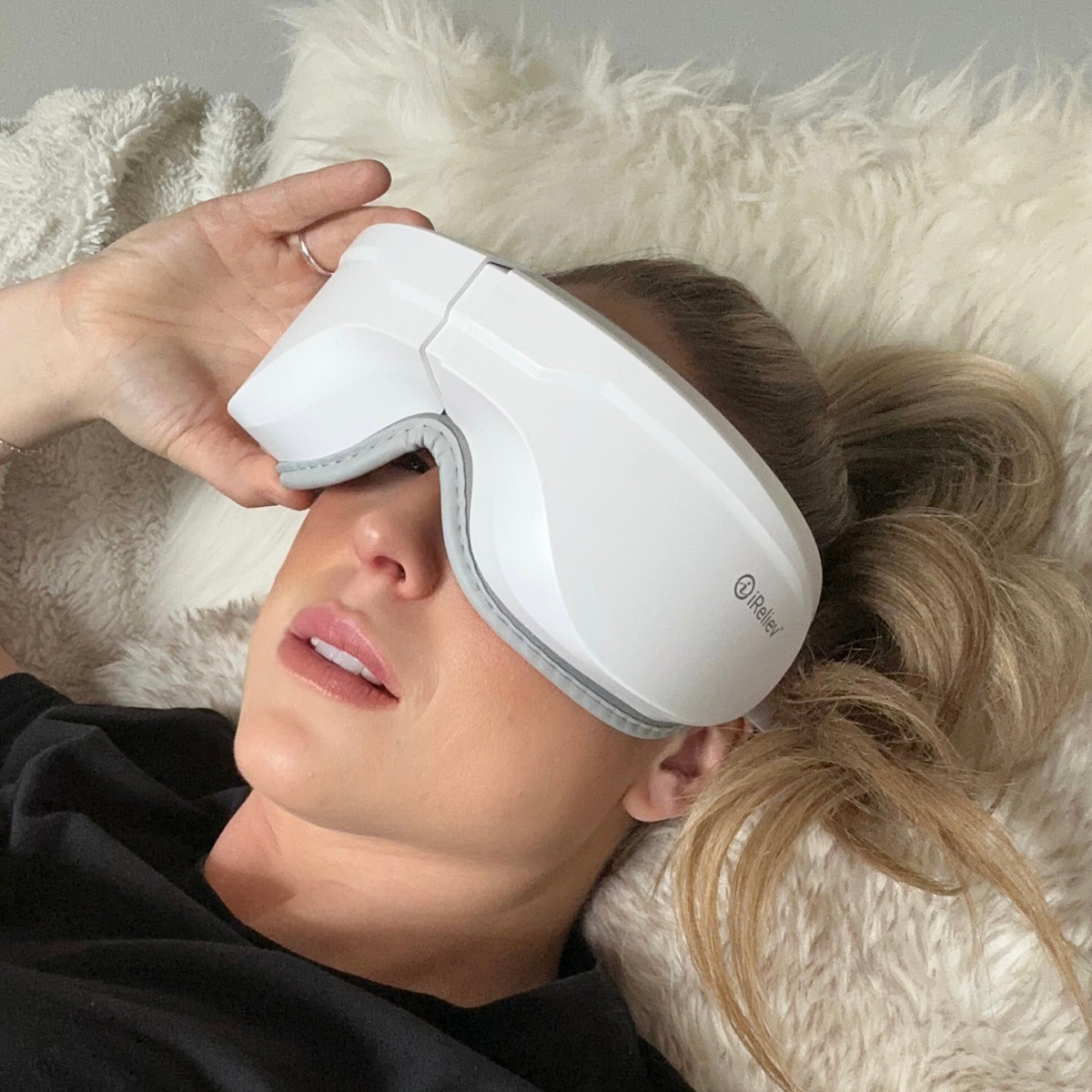 Person using a white eye mask on a fluffy white pillow
