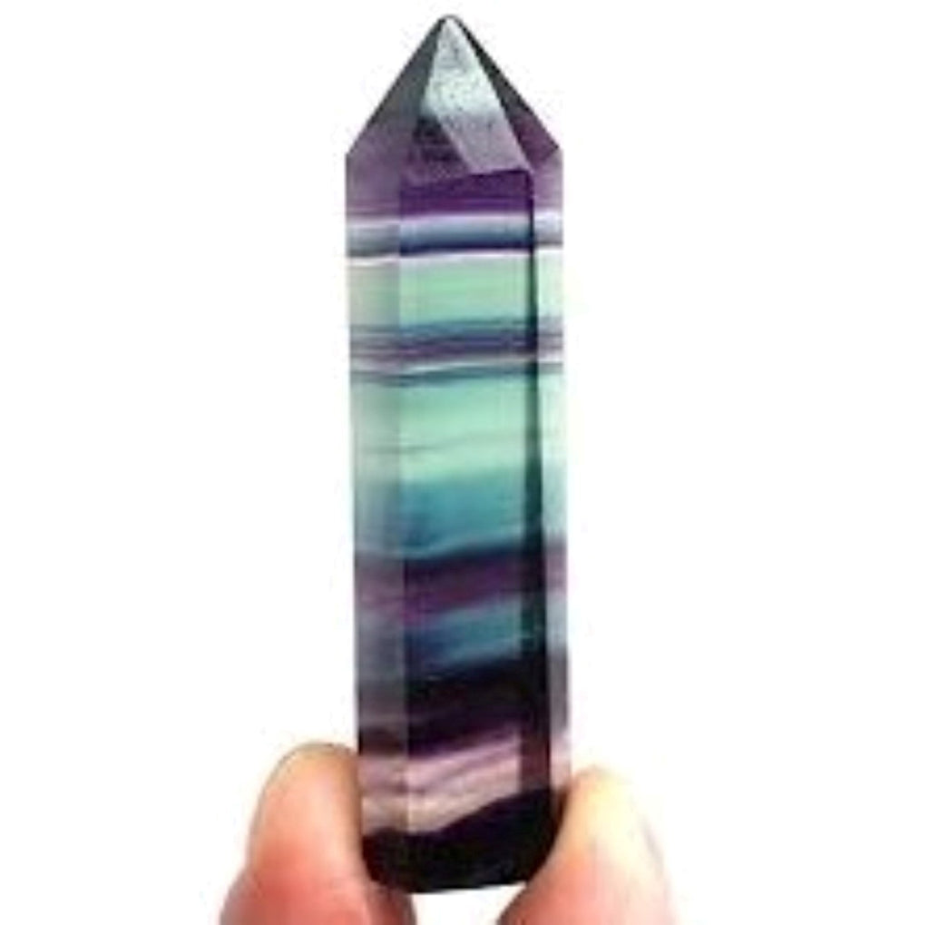A hand holding a Fluorite Crystal Obelisk.