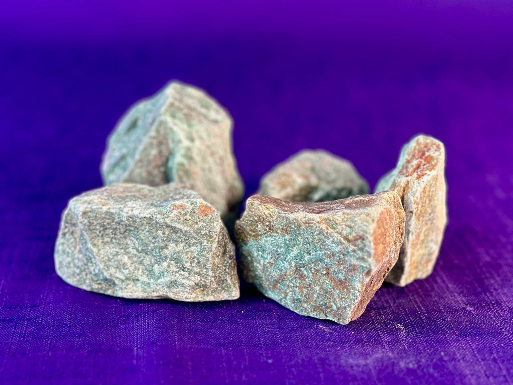 Five colorful gemstones on a purple fabric.