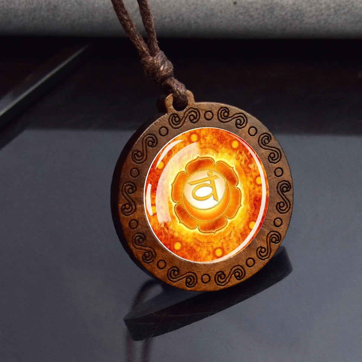 Wooden pendant with orange and yellow design on a dark surface