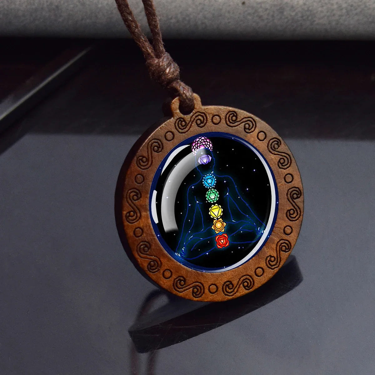 Wooden pendant with chakra design on a dark surface