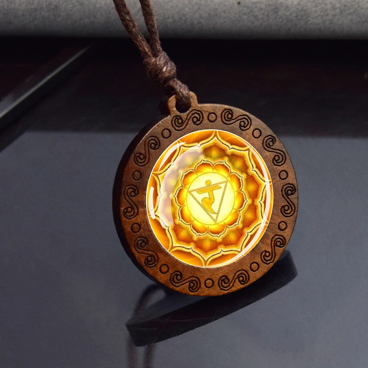 Wooden pendant with a glowing yellow center on a dark surface