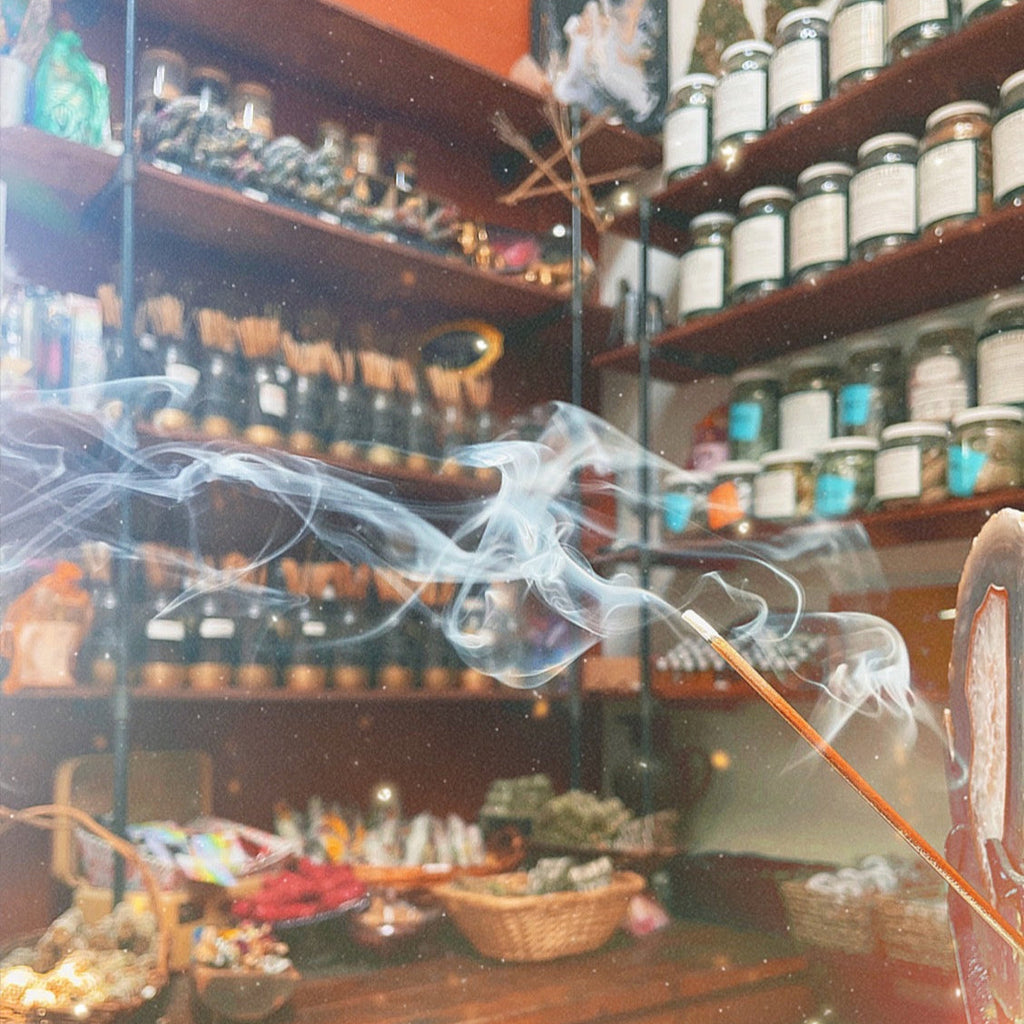 Many jars of incense sticks on shelves with one burning stick in the forefront if the picture.