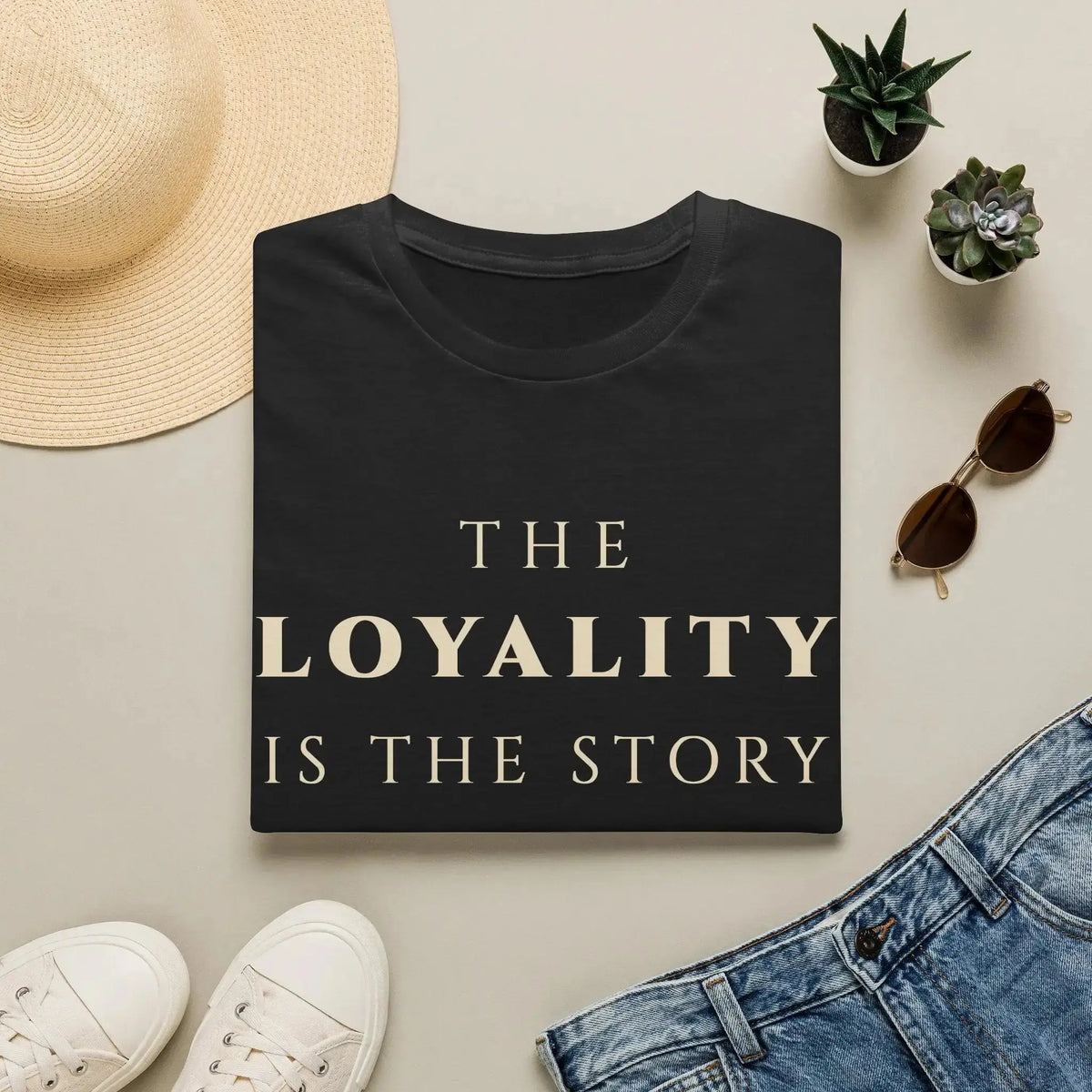Black t-shirt with 'The Spirituality is the Story' text on a light surface with casual items.