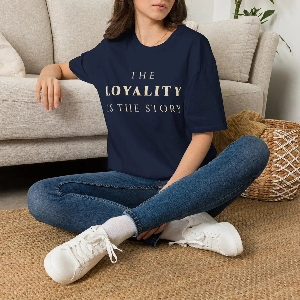 Person wearing a navy blue t-shirt with graphic design sitting on a carpeted floor.