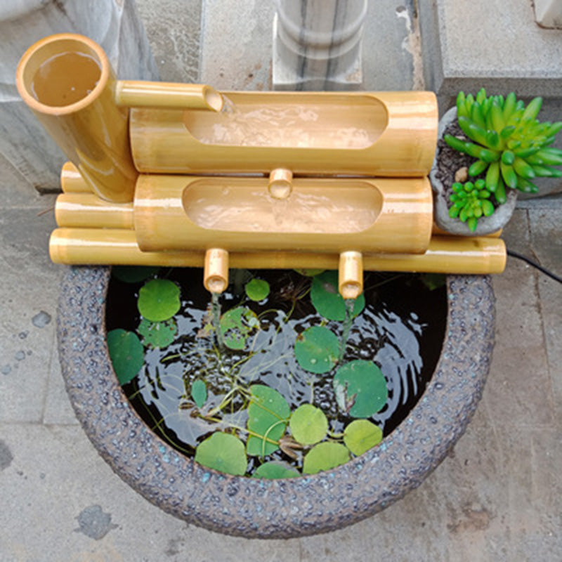 Picture of a Handcrafted Bamboo Water Spout sitting on top of a gray container filled with water.