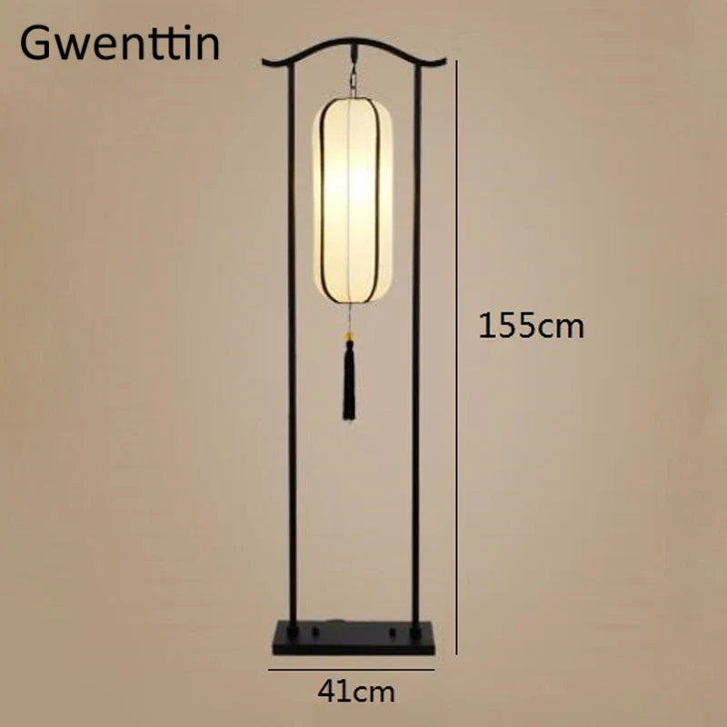 A black metal floor lamp with a glowing rectangular lantern shade and tassel, shown with dimension labels reading 155cm height and 41cm base width on a plain beige background.