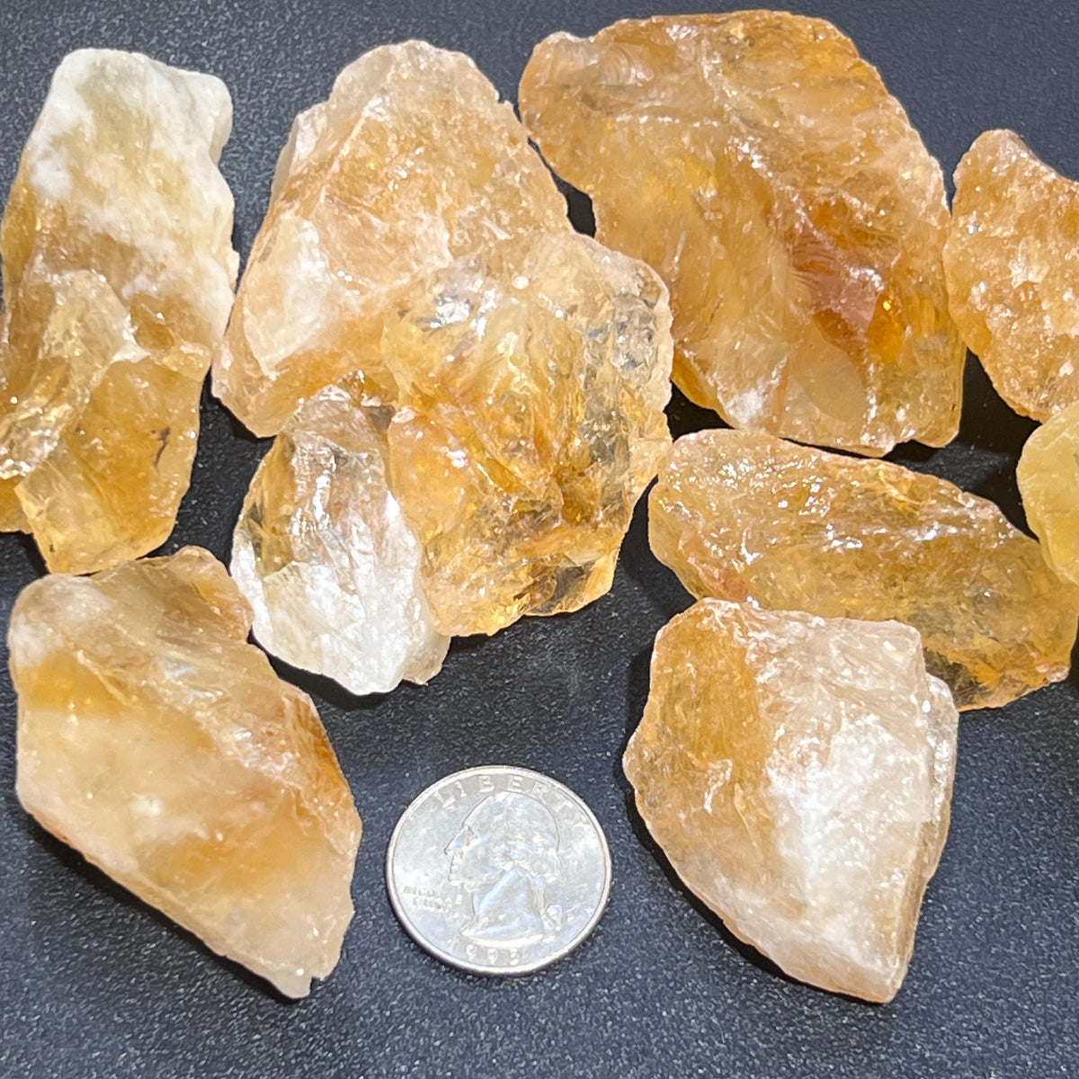 Large rough citrine crystal stones shown with a quarter for size reference
