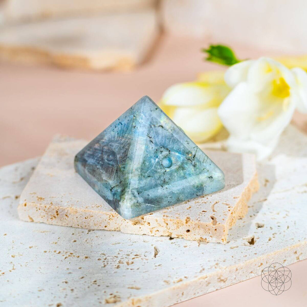 Pyramid-shaped blue crystal on a white surface with a blurred background
