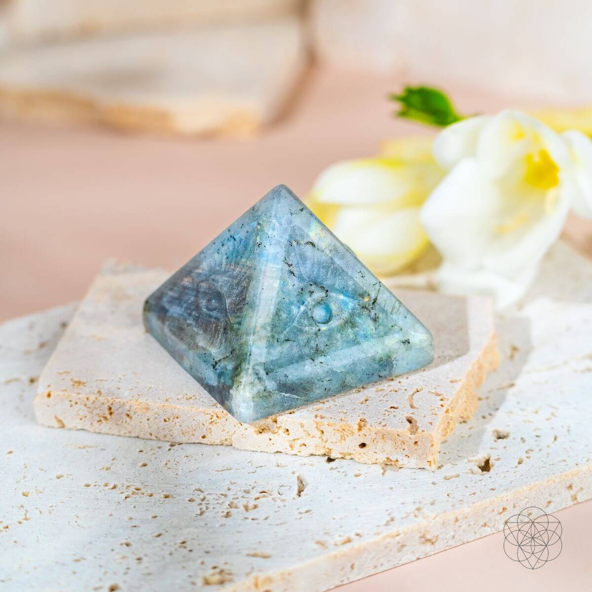 Pyramid-shaped blue crystal on a white surface with a blurred background