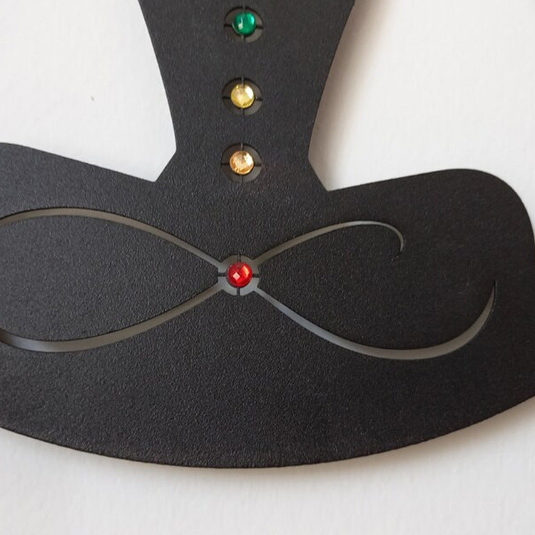 Black mask with red, green, and gold eye holes on a white background
