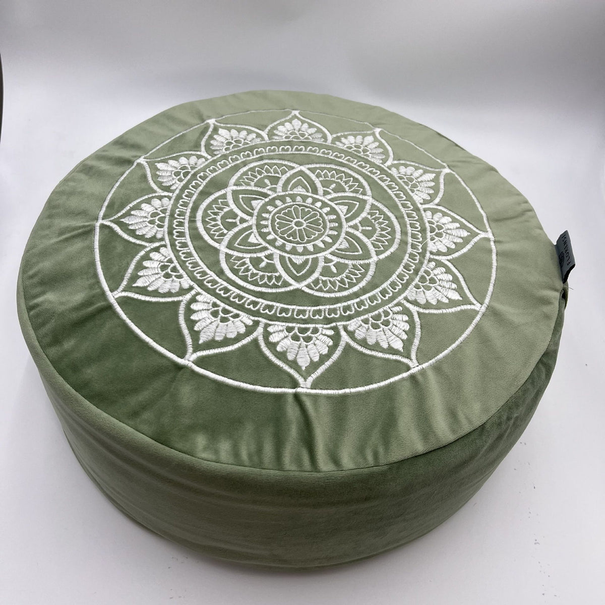 Green cushion with white mandala design on a white background