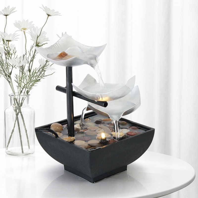 Tabletop water fountain with white bowls and pebbles on a white surface
