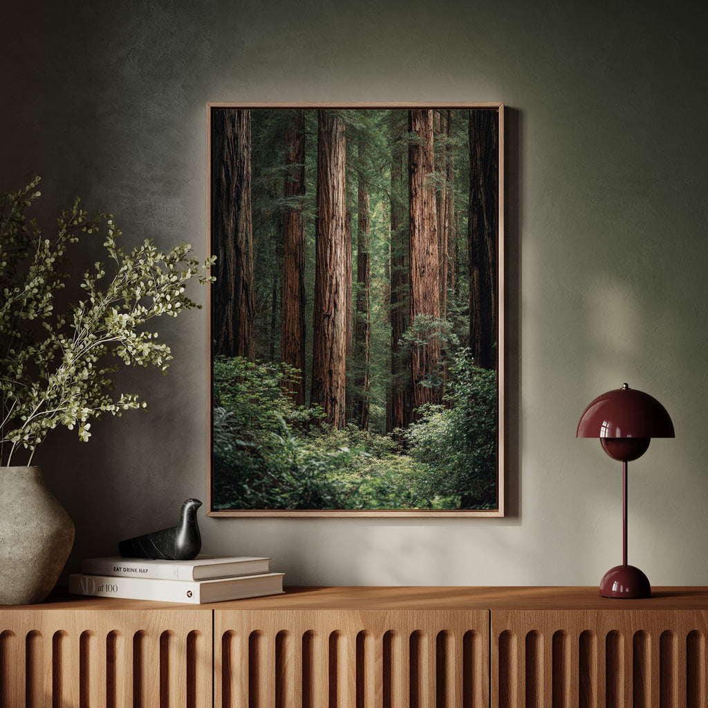 Framed forest artwork on a wall above a wooden console table with decorative items.