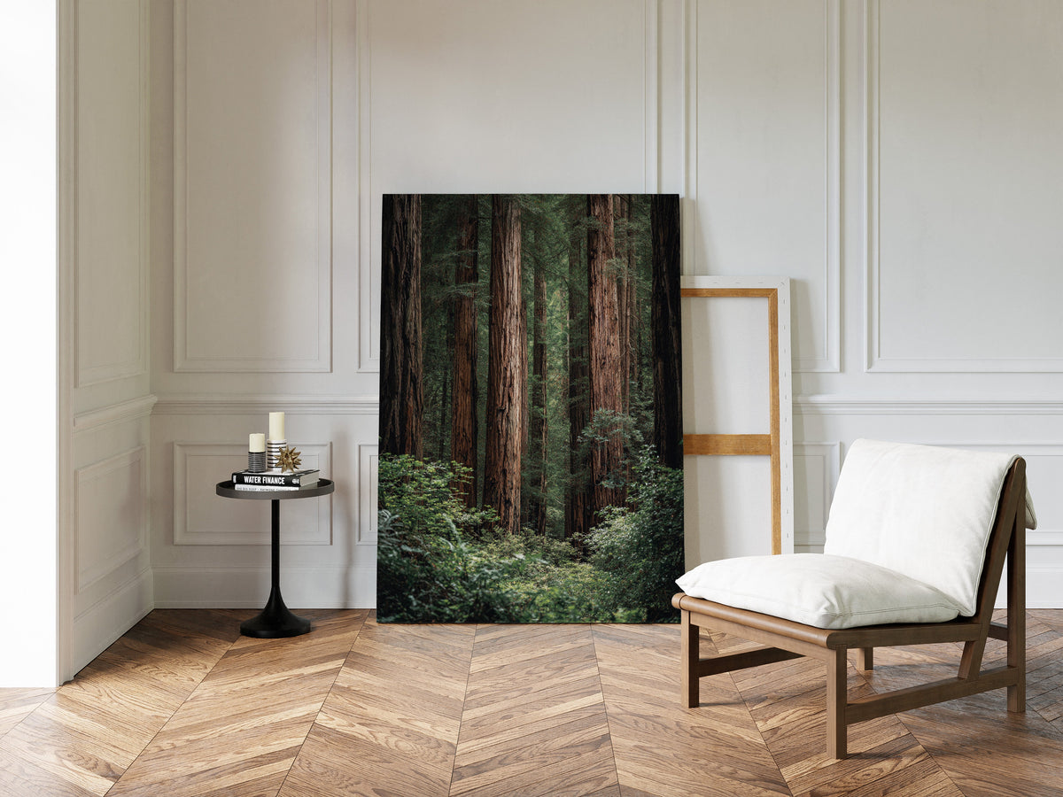 Room interior with a large forest print on the wall, a chair with a white cushion, and a small table.