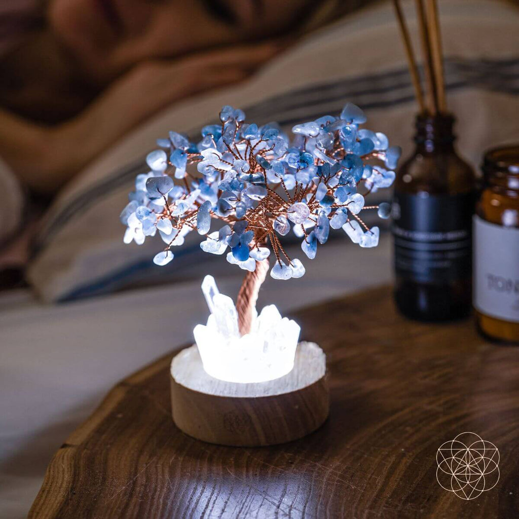 Decorative tree lamp with blue and white branches on a wooden surface.