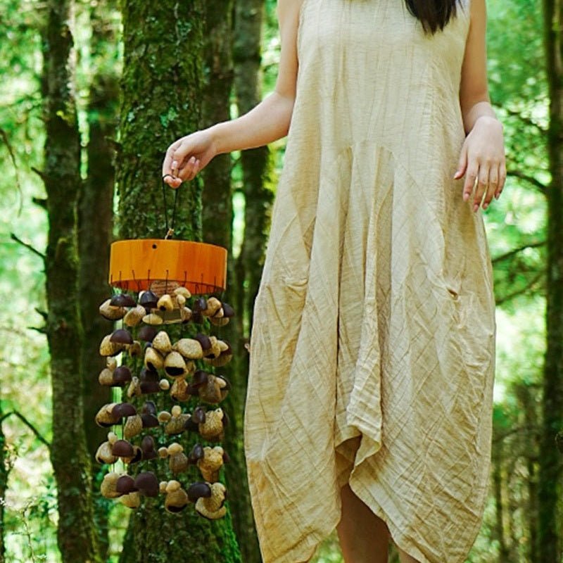 Picture of a woman holding a seed pod wind chime with her right hand.