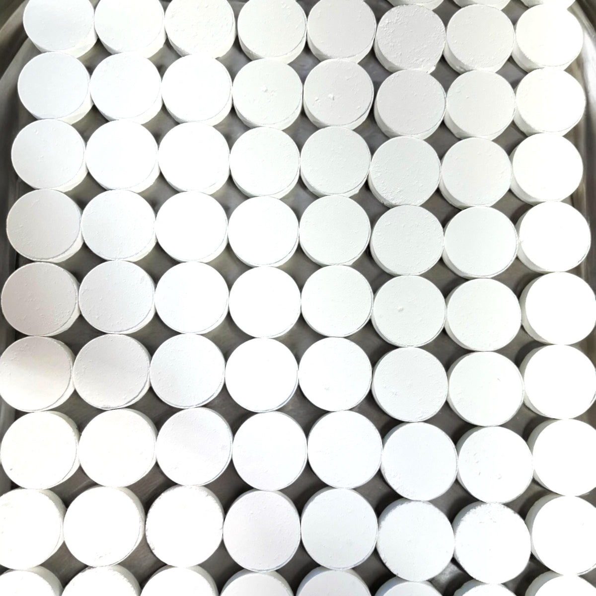 A dense grid of small white cylindrical discs or caps arranged tightly together, filling the frame.
