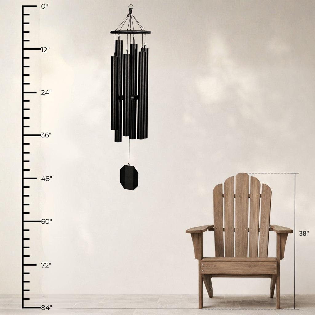 Black wind chime next to a wooden Adirondack chair with measurements on a neutral background
