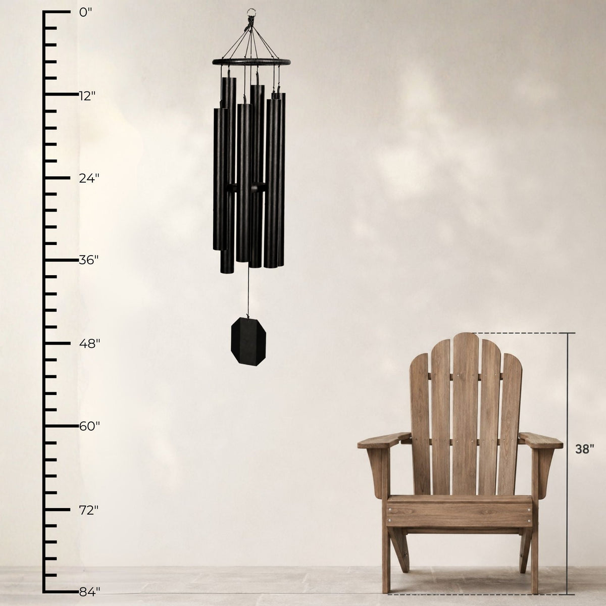 Black wind chime next to a wooden Adirondack chair with measurements on a neutral background