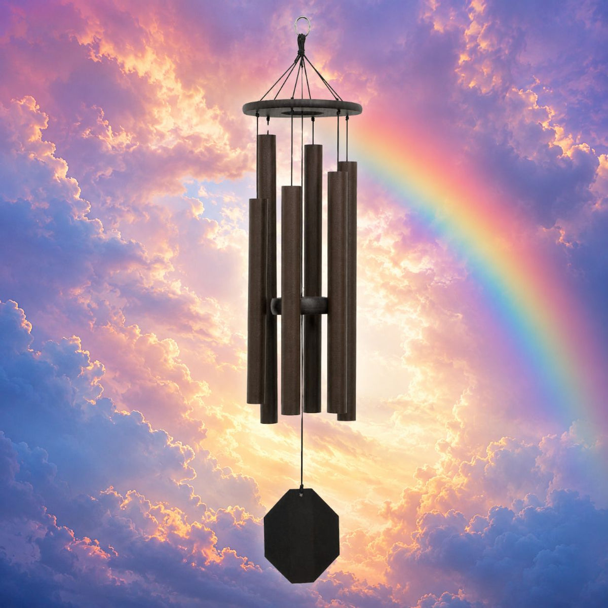A dark brown metal wind chime with multiple vertical tubes and a hanging octagonal weight, centered against a dramatic sky with pink, purple, and blue clouds and a rainbow arching behind it.