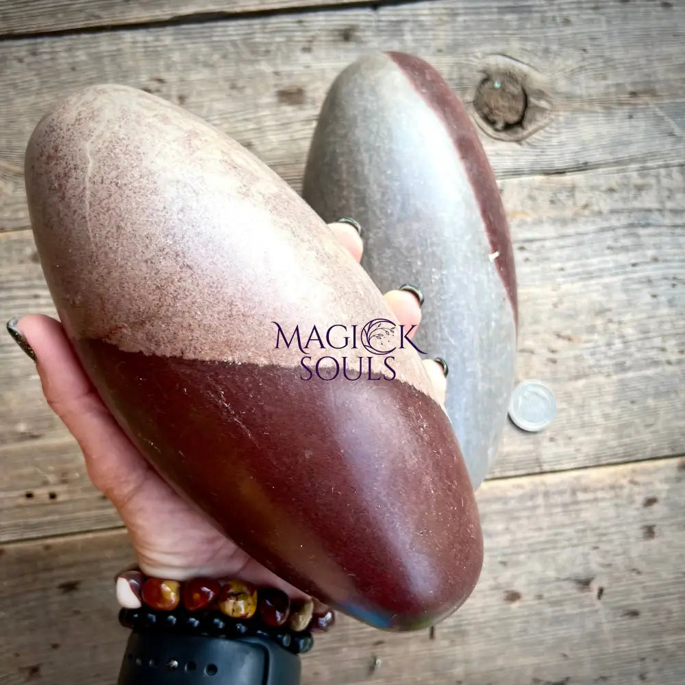 Heart-shaped stone held by a hand on a wooden surface with 'Magick Souls' branding.