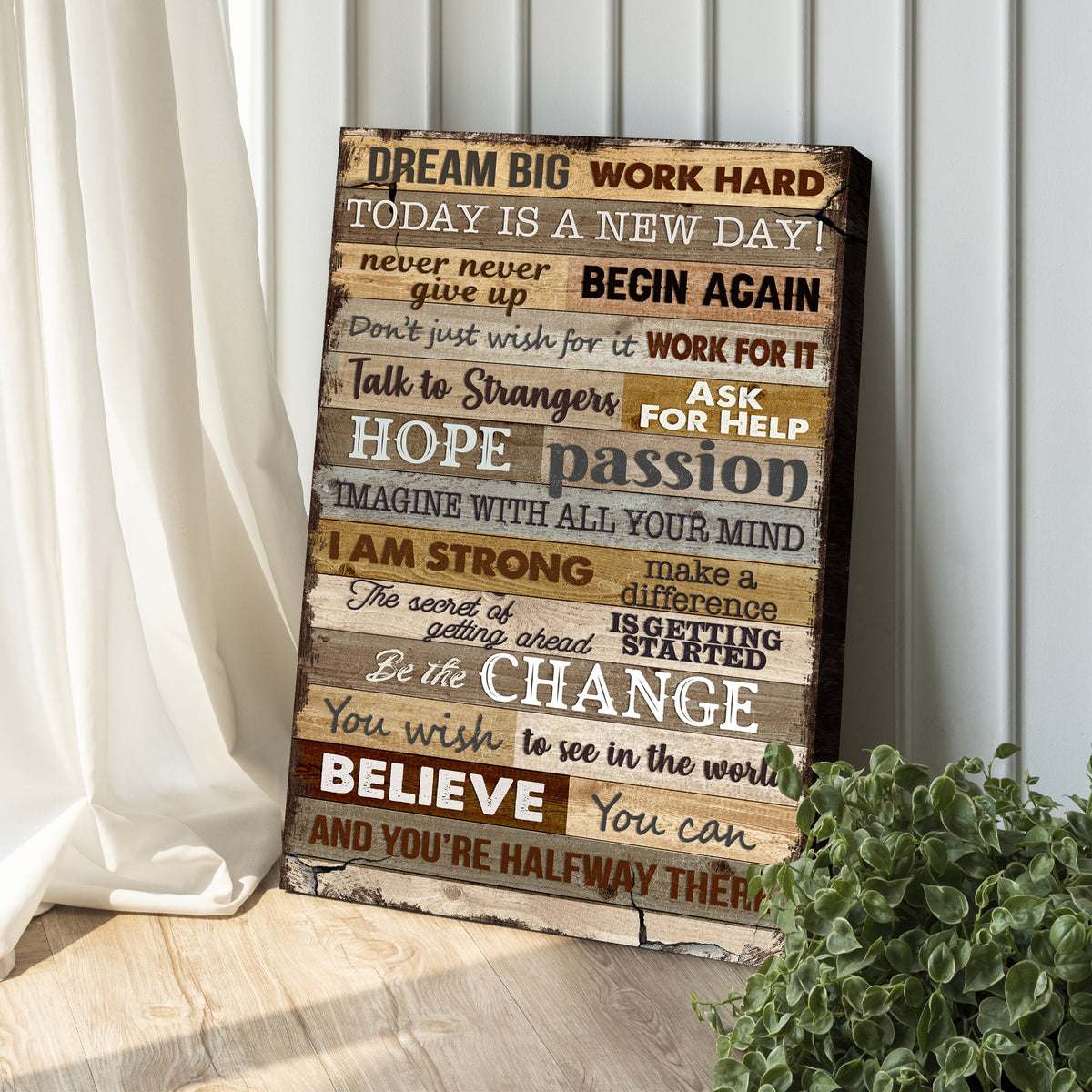 Wooden motivational plaque with inspiring quotes on a wall with a plant in the foreground