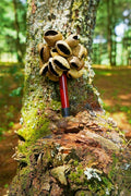 Decorative bouquet with a red and black handle on a tree stump in a forest setting
